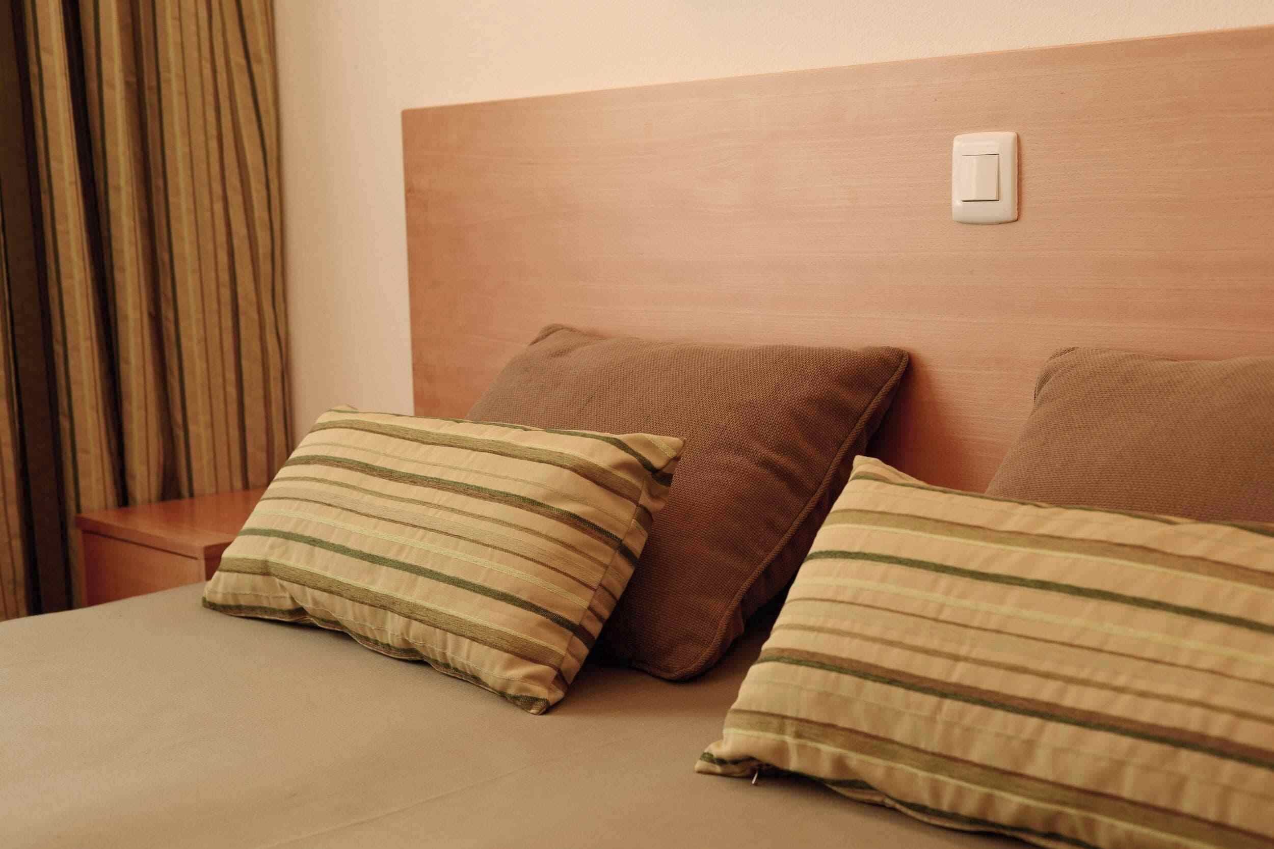A bed with striped pillows and a wooden headboard.