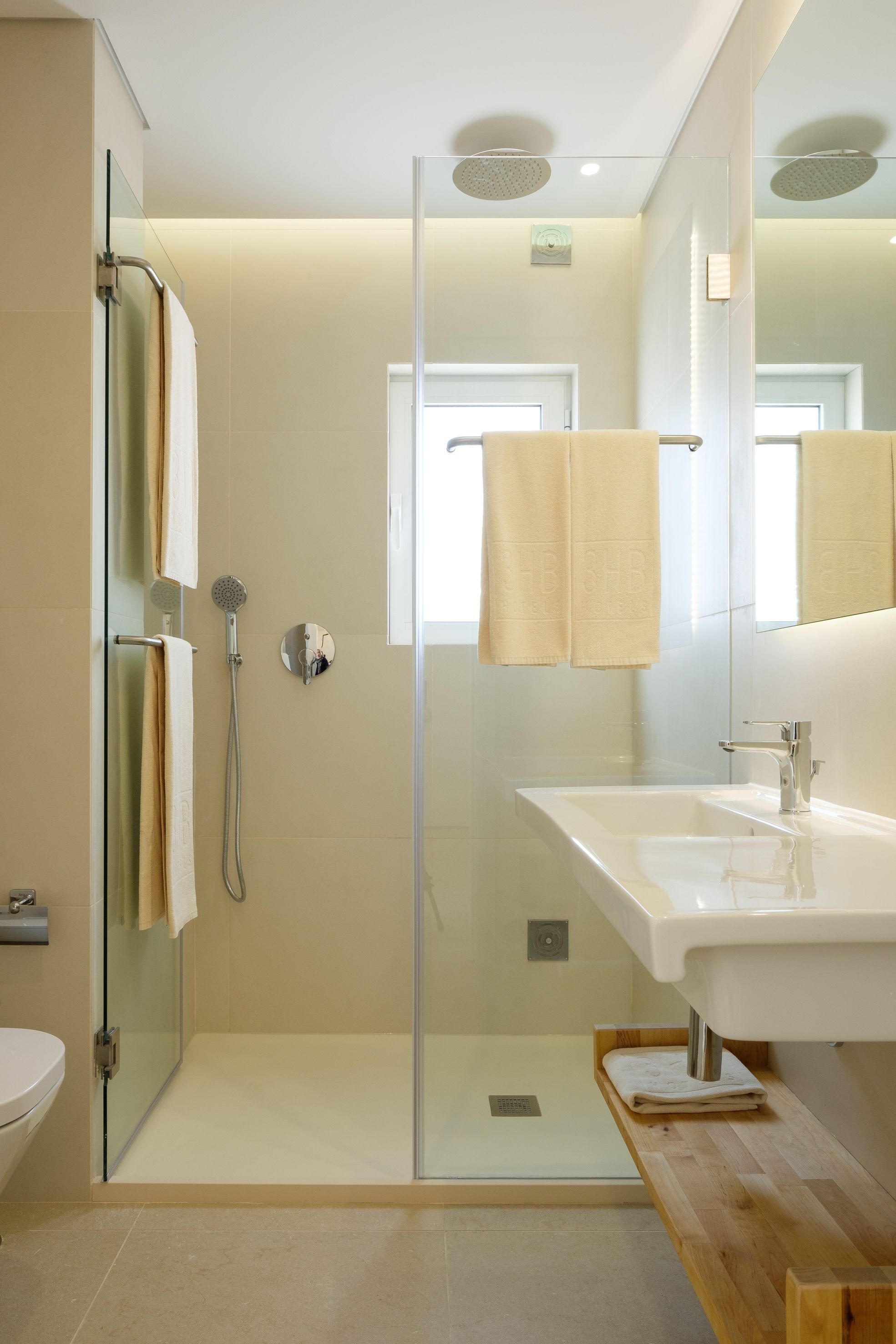 Une salle de bain moderne avec une douche à parois de verre, un lavabo blanc et un miroir au-dessus du lavabo.