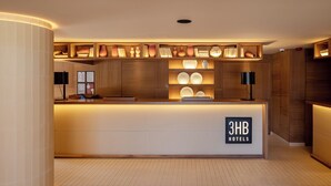 Ein Empfangsschalter mit Holzoptik und einem Schild mit der Aufschrift '3HB Hotels'.