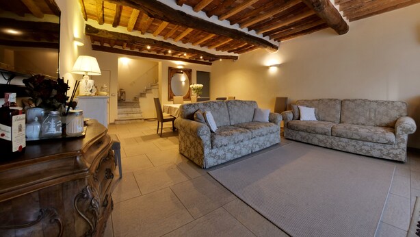 A spacious living room with a high wooden ceiling, two sofas, a coffee table, and a staircase leading to an upper level. - B&B La Bella Lucca (Lucca)