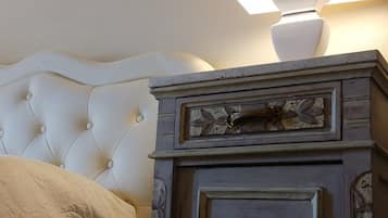 Une chambre à coucher avec une tête de lit capitonnée, une armoire en bois avec une porte et une lampe de chevet.