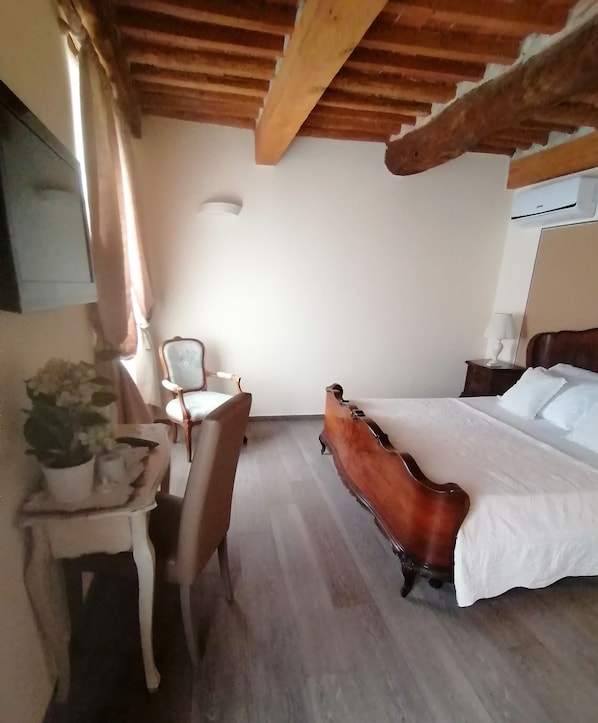 Un dormitorio con una cama de madera, un escritorio con una silla, una planta en maceta y una ventana con cortinas.