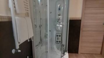 A bathroom with a glass-enclosed shower, a toilet, and a bidet.