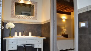 A bathroom with a white vanity, a mirror with an ornate frame, and a vase with white flowers. - B&B La Bella Lucca (Lucca)