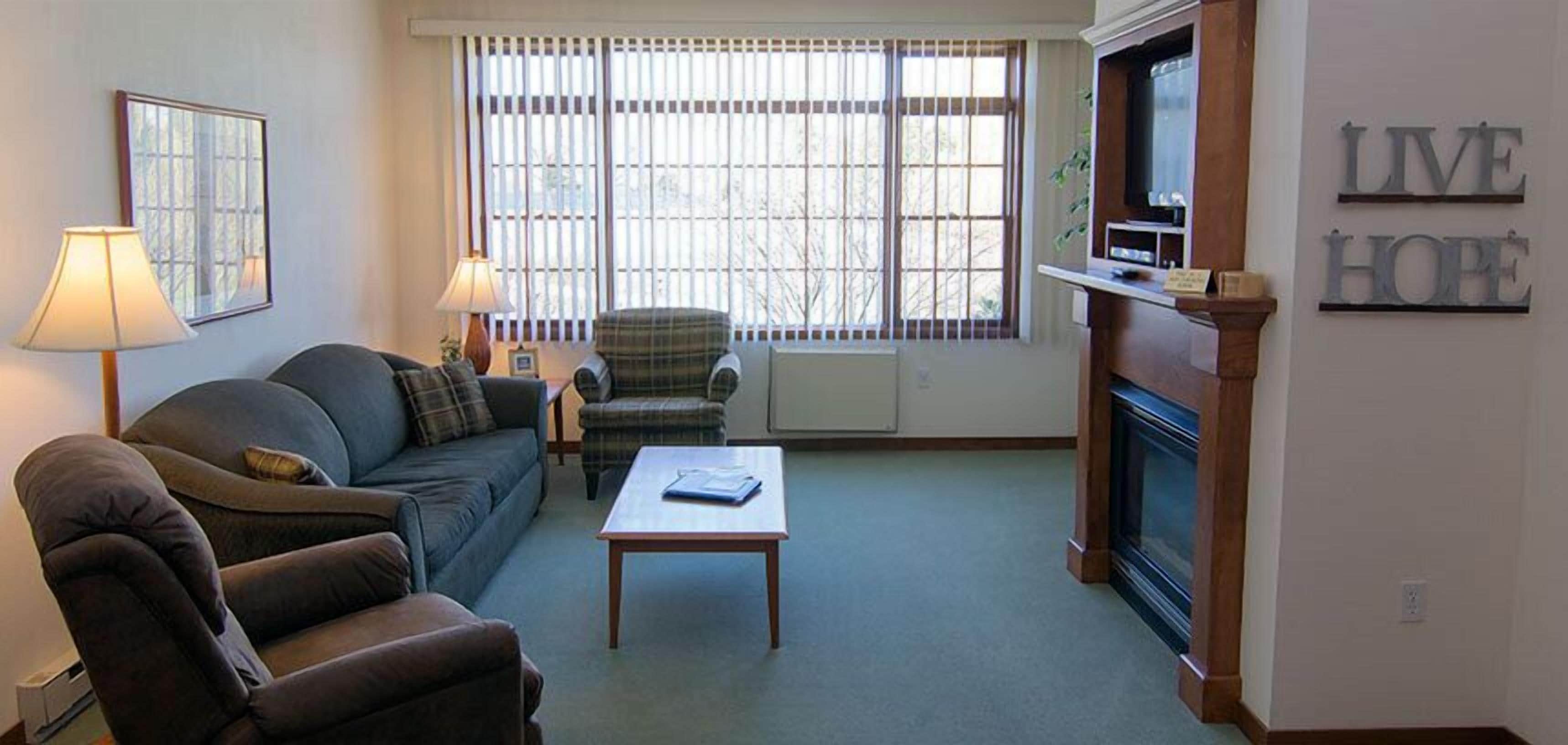 A living room with a sofa, armchairs, a coffee table, a fireplace, and a television.