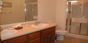 A bathroom with two sinks, a toilet, and a glass shower enclosure. - Scandinavian Lodge (Sister Bay)