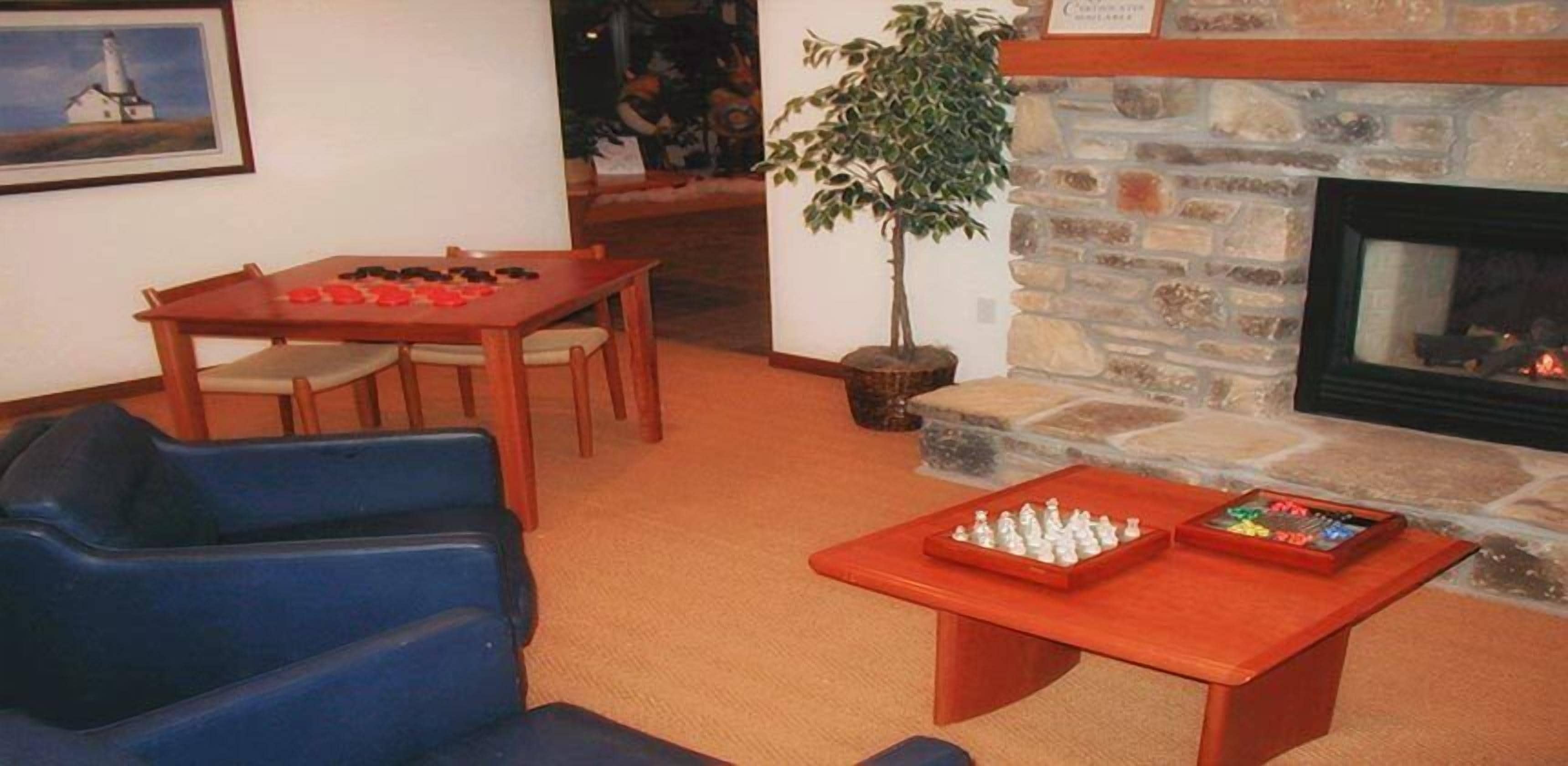 Ein gemütliches Wohnzimmer mit Kamin, einem Esstisch mit Stühlen und einem Couchtisch mit Schachfiguren.