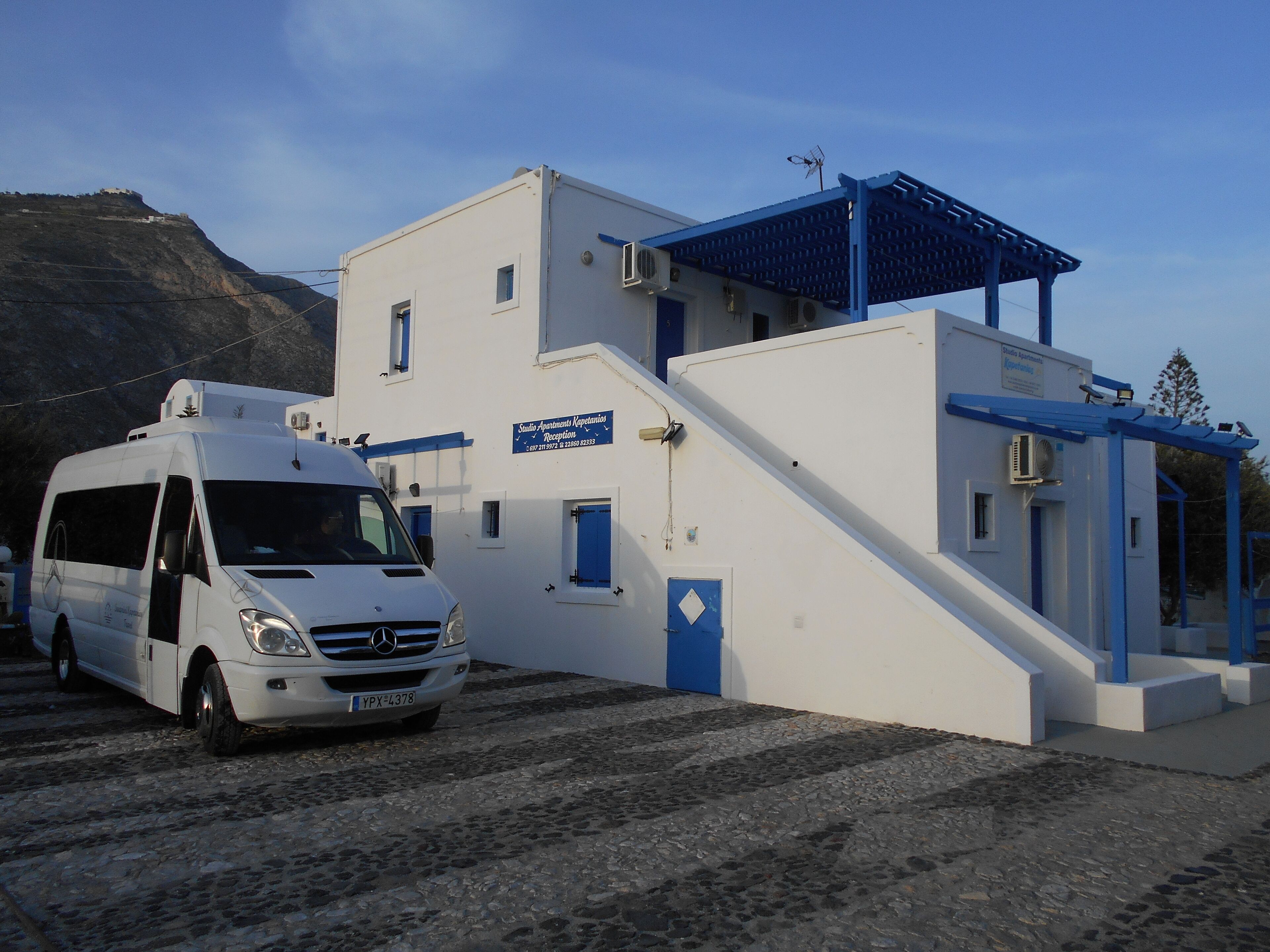 A white building with blue accents, a reception area, and a van parked in front.