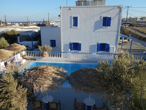 A building with a pool, outdoor seating, and a view of the sea. - Studios Apartments Kapetanios (Santorini)