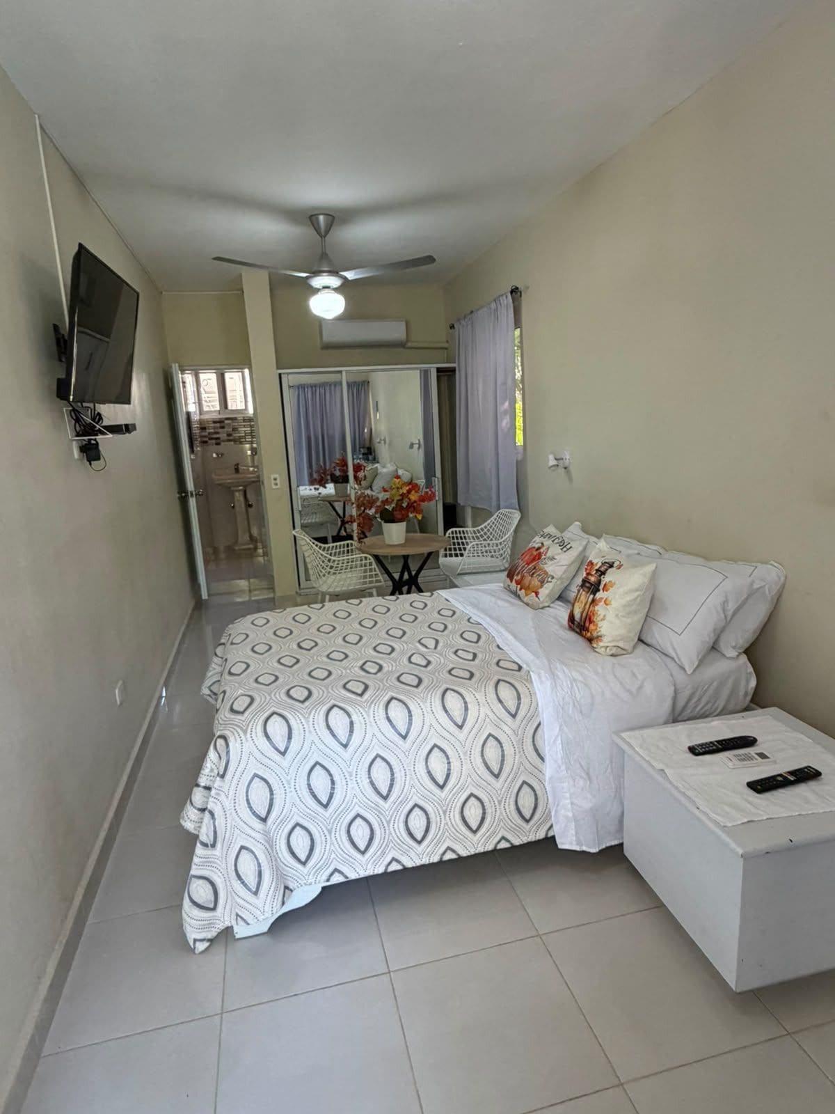 A bedroom with a bed, a nightstand, a TV, and a ceiling fan.