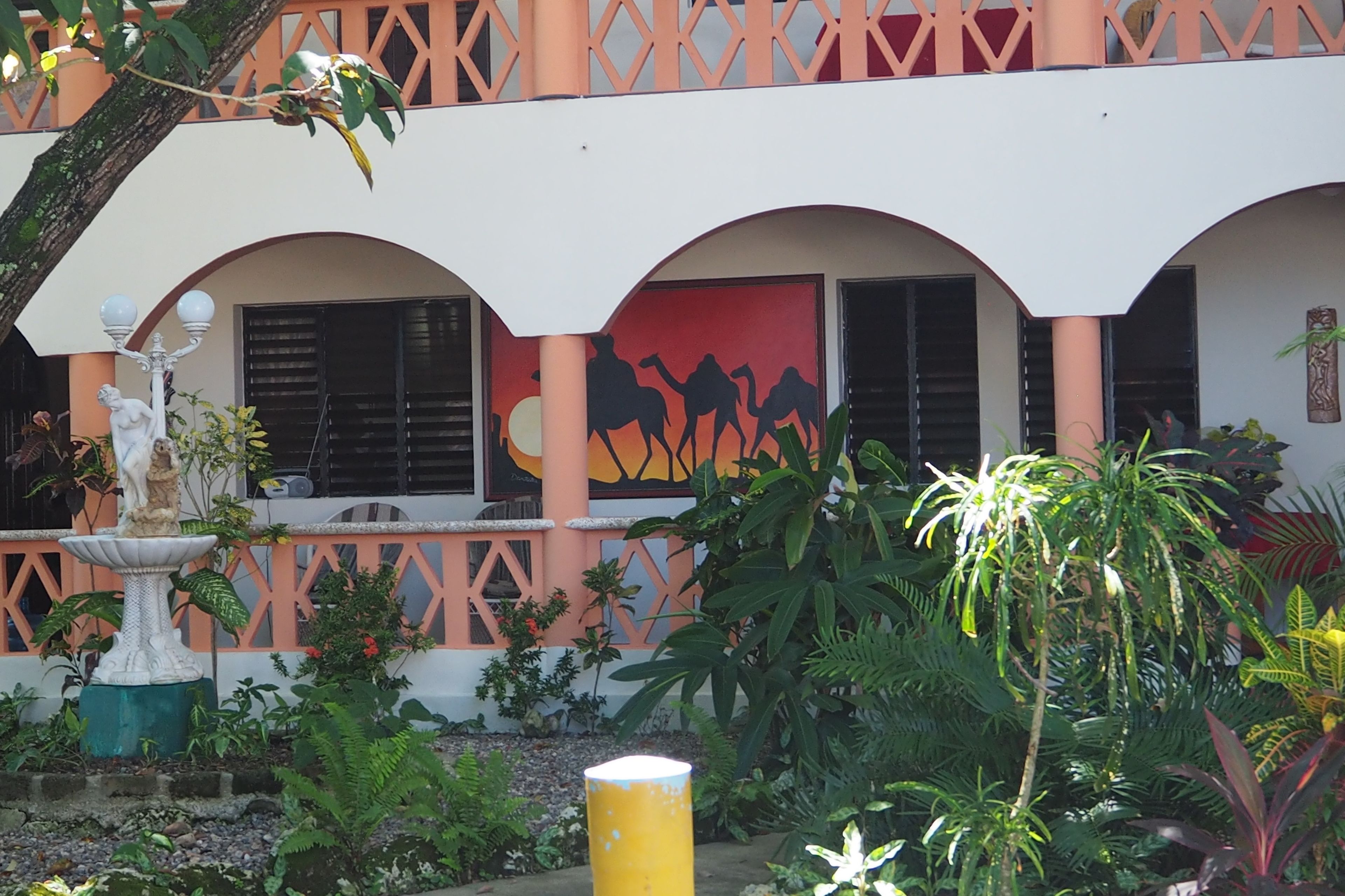 Un edificio con fachada blanca, celosías naranjas y un mural de camellos.