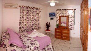 Une chambre à coucher comprenant un lit, une commode, un miroir et un climatiseur.