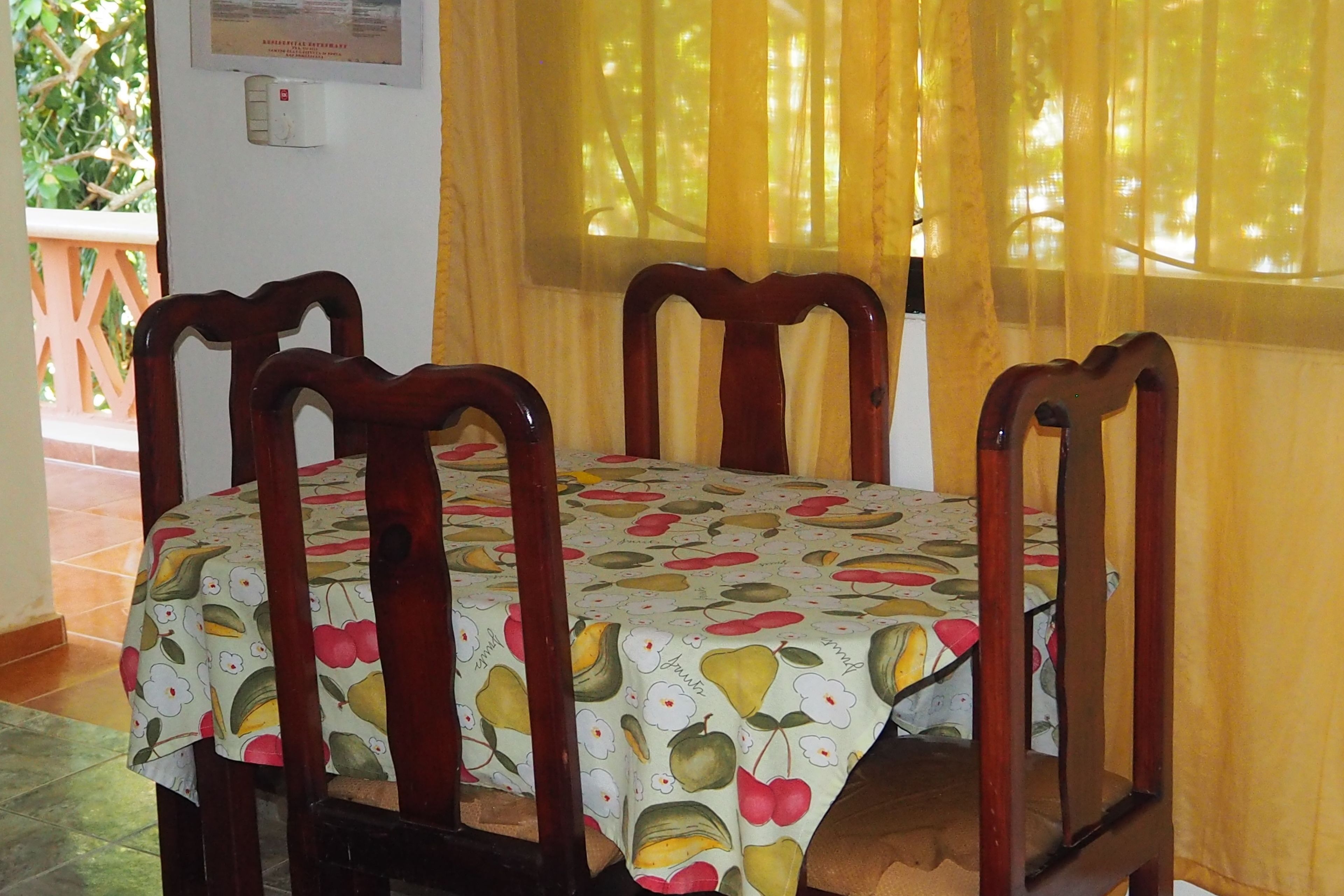 Ein Essbereich mit einem Tisch, der mit einer Tischdecke mit Obstmuster bedeckt ist, umgeben von Holzkästen.