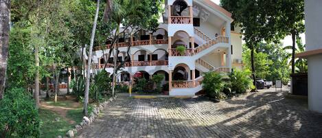 A multi-story building with a central courtyard, balconies, and a paved walkway.
