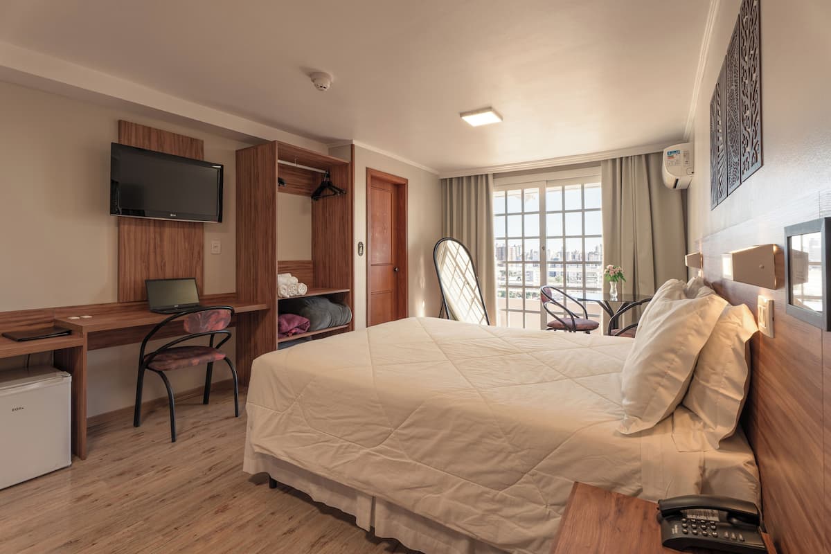 Une chambre d’hôtel équipée d’un lit, d’un bureau, d’une chaise, d’une télévision et offrant une vue sur la ville.