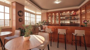 Una zona de bar con armarios de madera, taburetes y una mesa redonda con sillas.