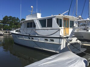 A white yacht docked at a marina with a cabin and a covered deck area.