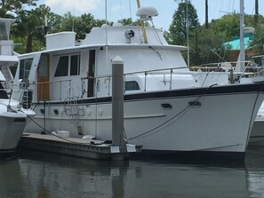 A white yacht docked at a marina with a cabin, windows, and a small deck area.