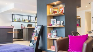 A modern lobby with a reception desk, seating area, and a magazine rack. - Campanile PRIME - Metz Centre Gare (Metz)