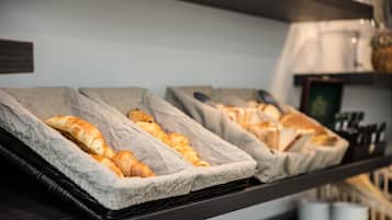 Een bakkerijvitrine met croissants en andere gebakjes in manden.