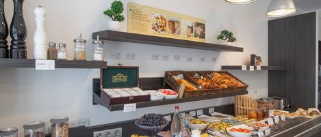 Un bufé de desayuno con diversos alimentos, salsas y una exhibición de tés.