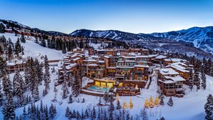 Un complejo turístico nevado con varios edificios, una piscina central y árboles circundantes.