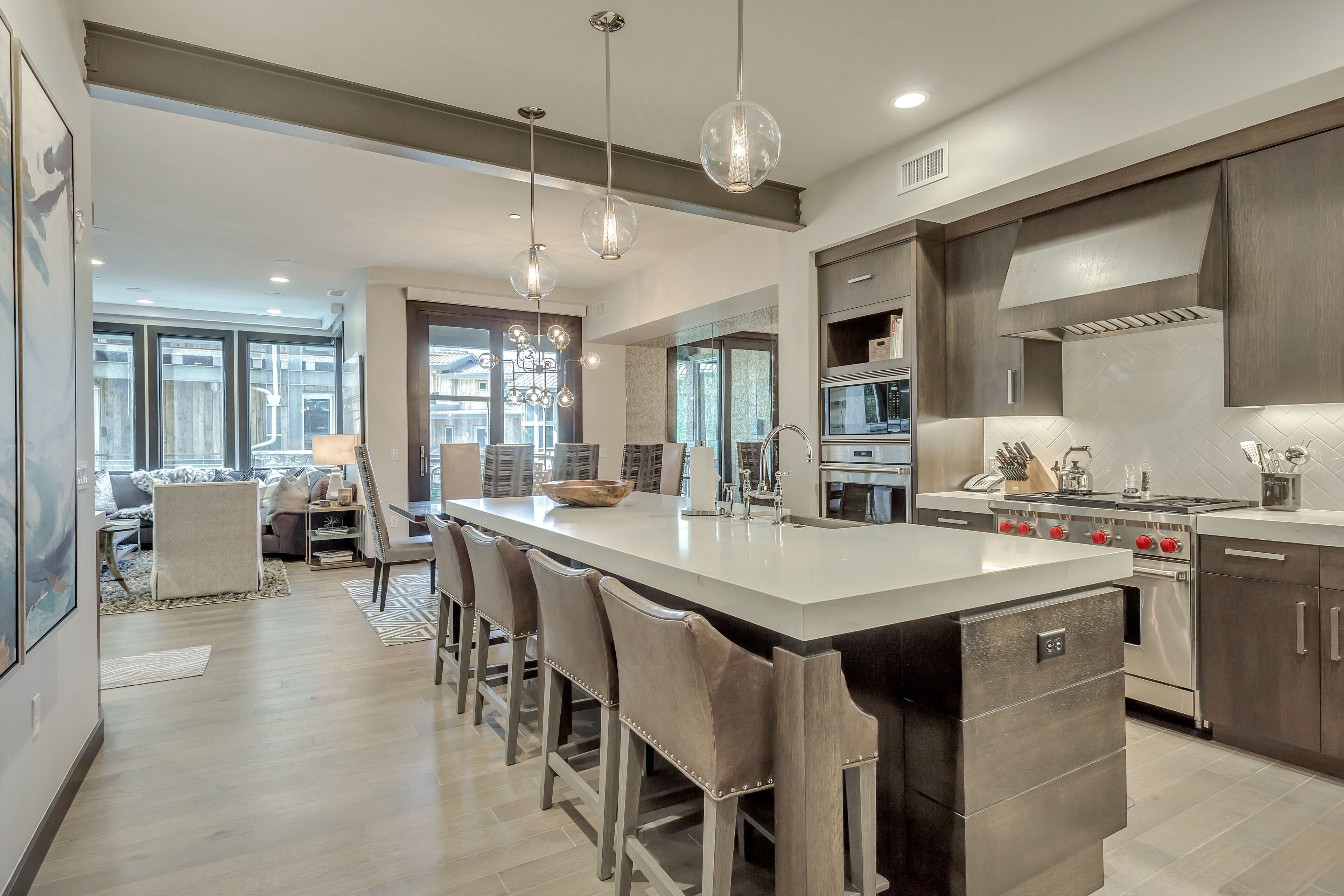 A modern kitchen with a large island, stainless steel appliances, and pendant lighting.