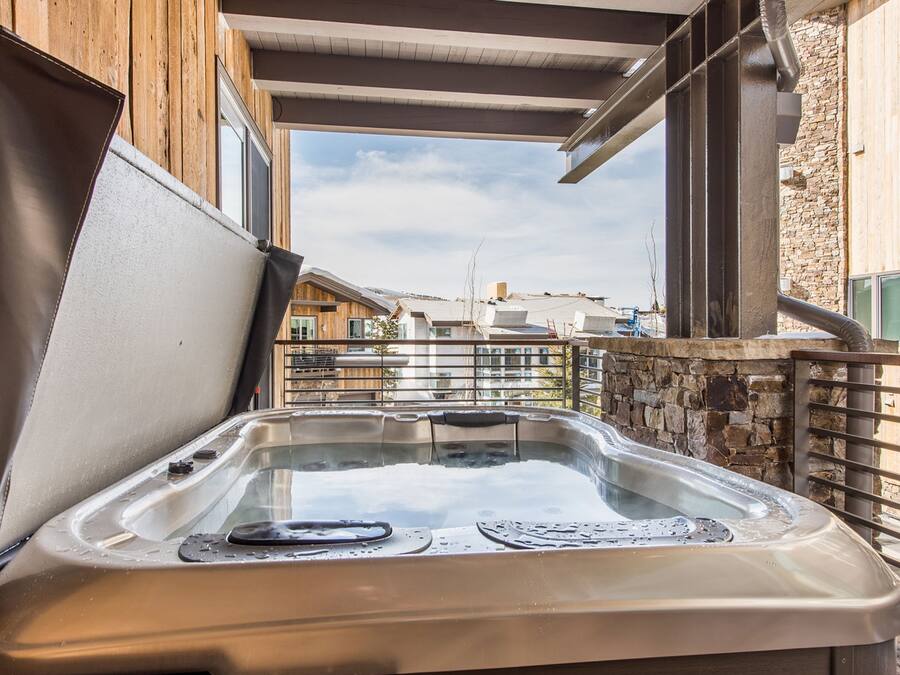 A hot tub in an outdoor setting with a wooden deck and stone wall.