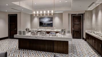 A modern hotel lobby with a central reception desk, a large abstract painting above the counter, and a patterned floor.