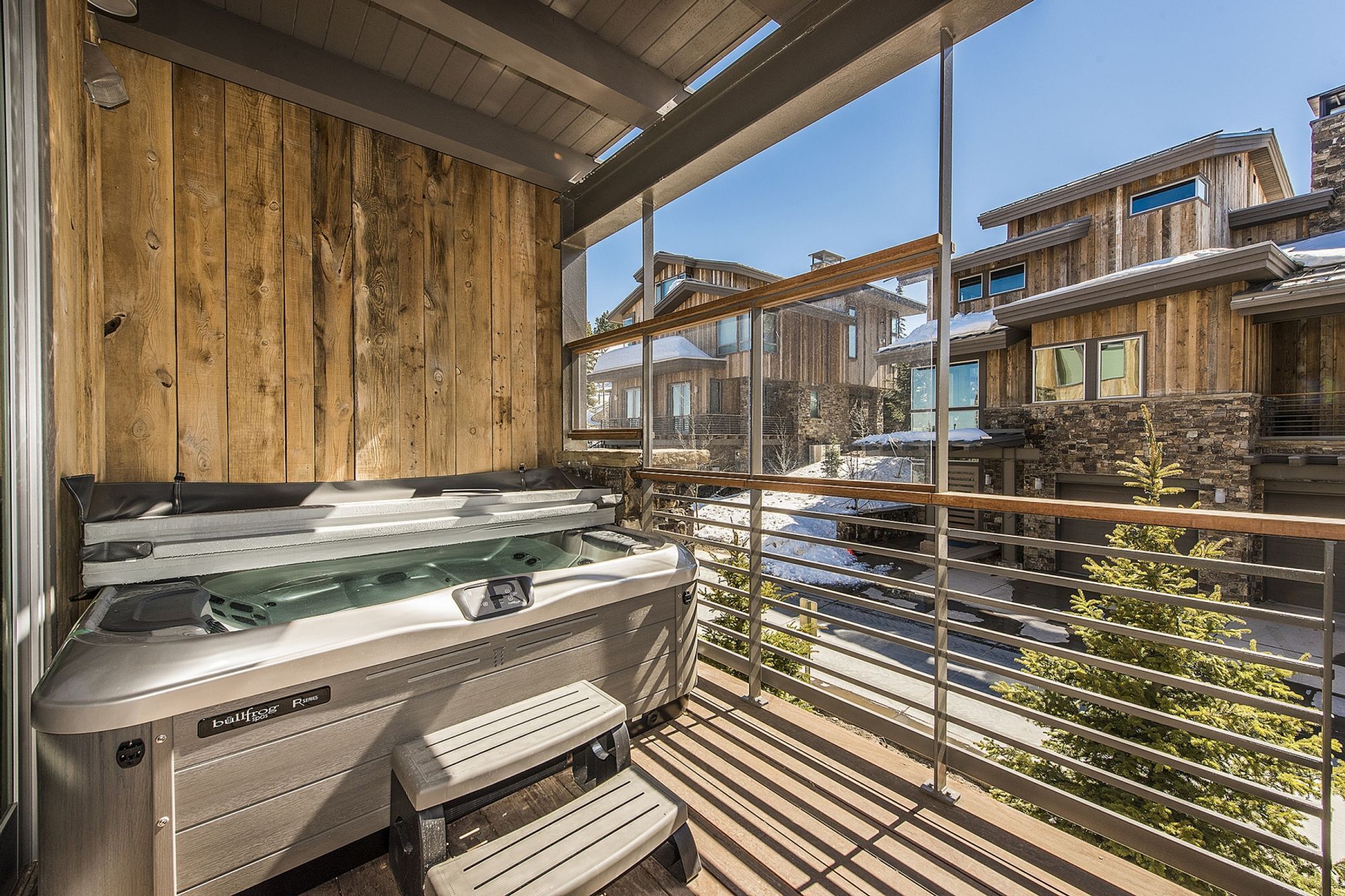 Ein Whirlpool auf einer Holzterrasse mit Blick auf benachbarte Häuser.