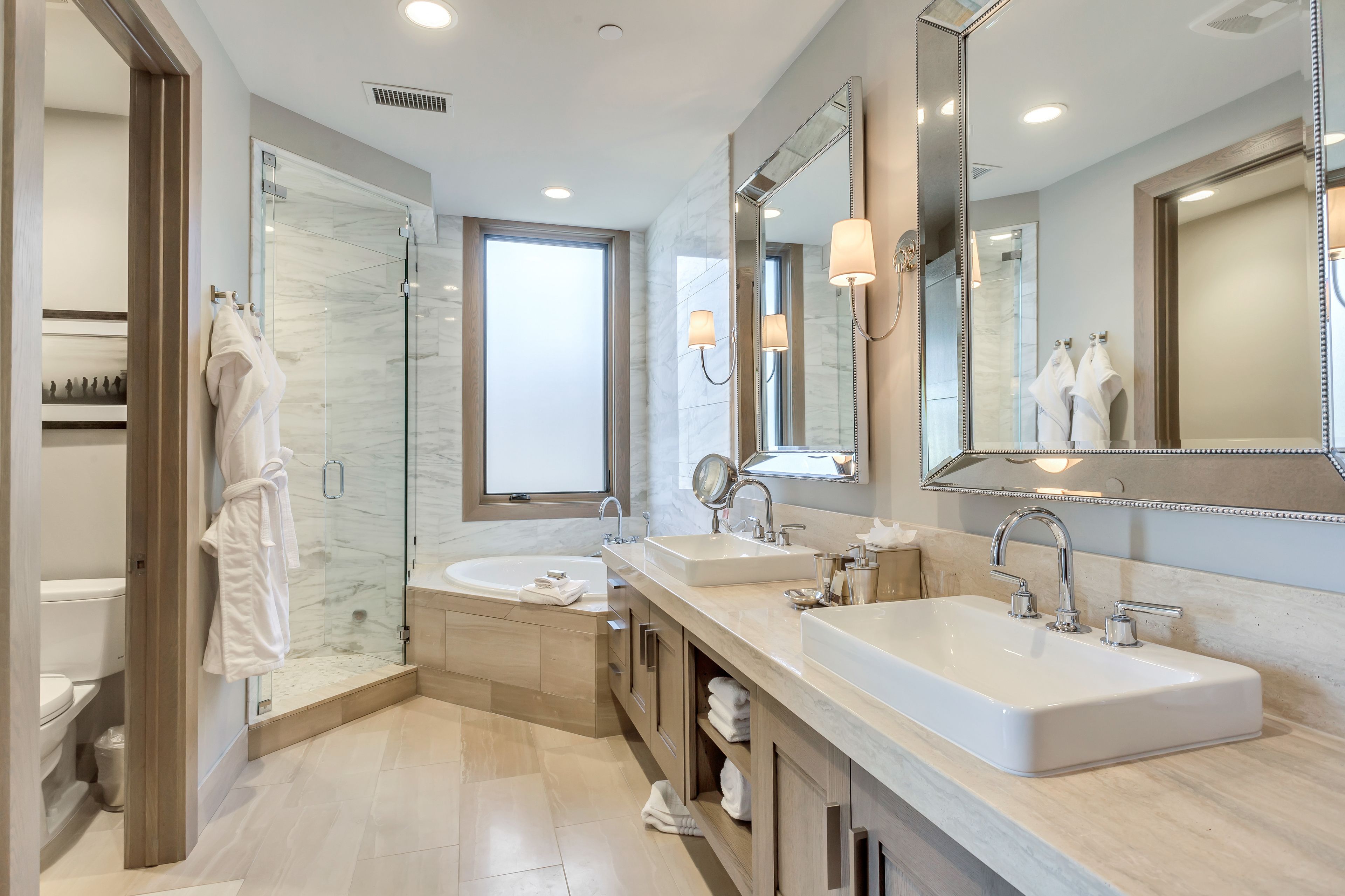 A modern bathroom with two sinks, a glass shower enclosure, and a large mirror.