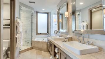 A modern bathroom with two sinks, a glass shower enclosure, and a large mirror.