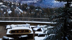 Un espacio al aire libre cubierto de nieve con una chimenea, con vistas a un paisaje montañoso.