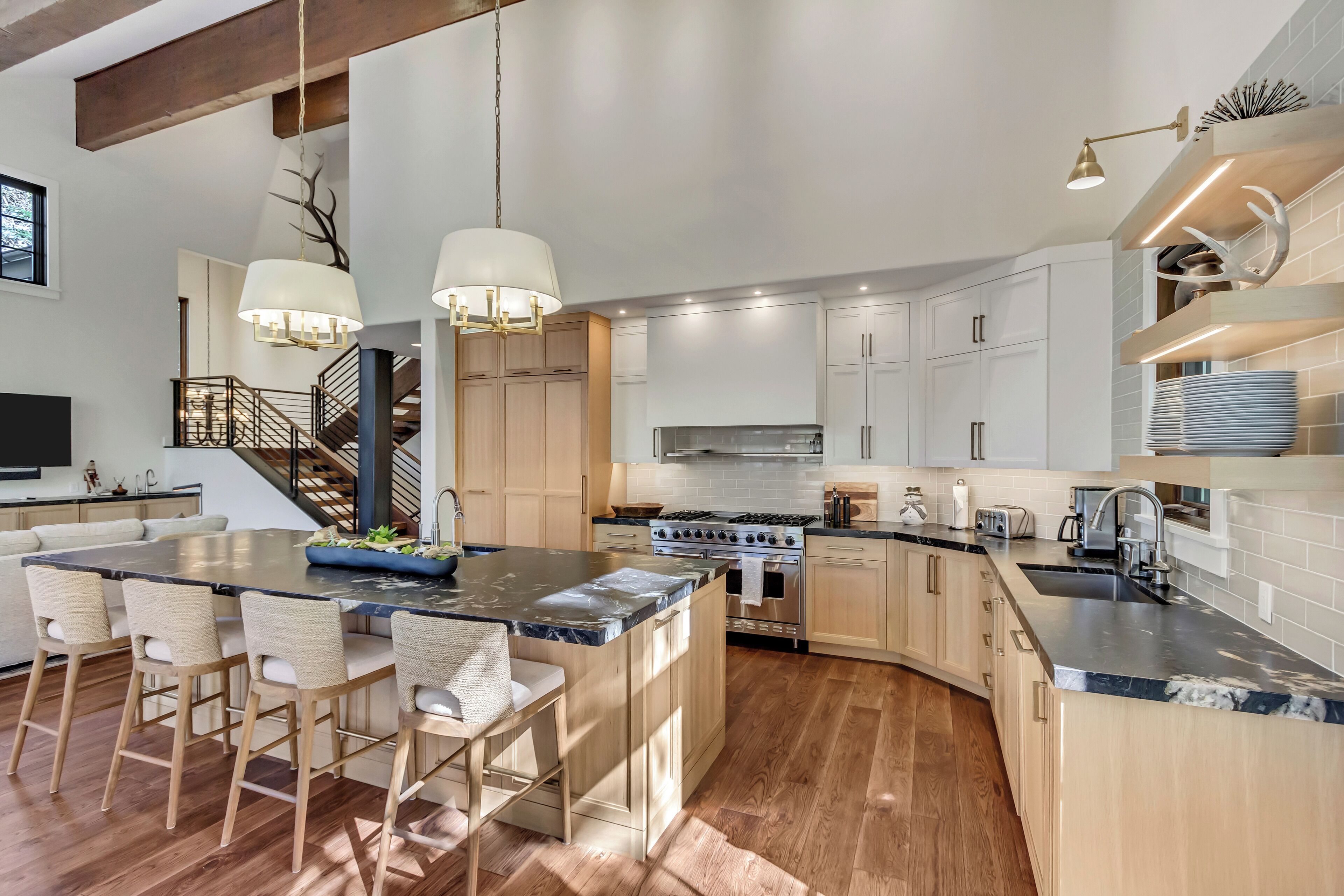 A modern kitchen with a large island, wooden cabinets, and stainless steel appliances.