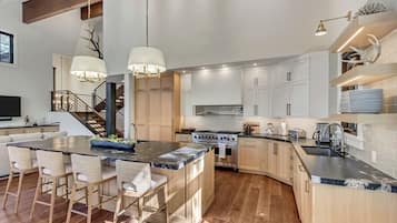 A modern kitchen with a large island, wooden cabinets, and stainless steel appliances.