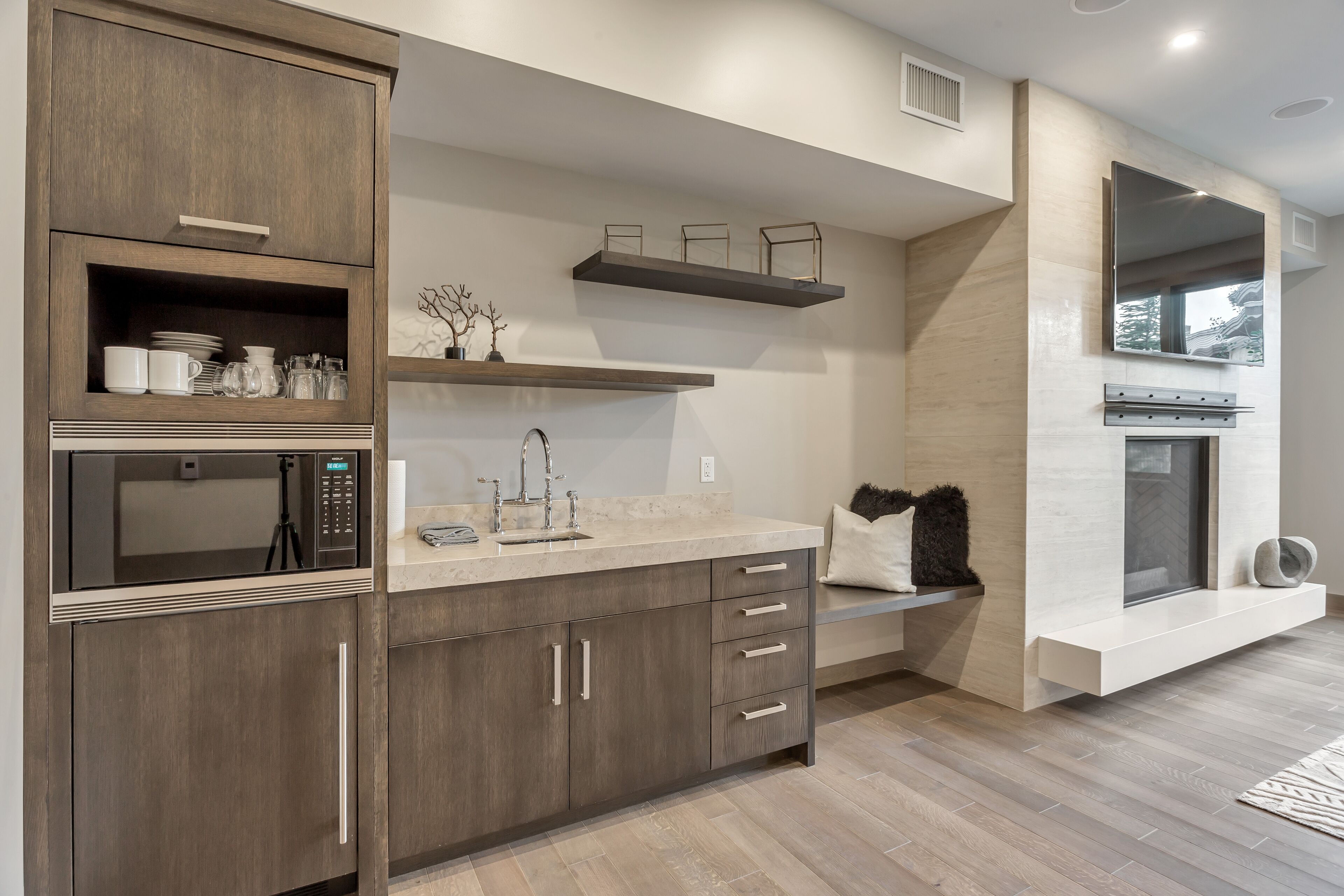 A modern kitchen with built-in appliances, wooden cabinets, and a large window.