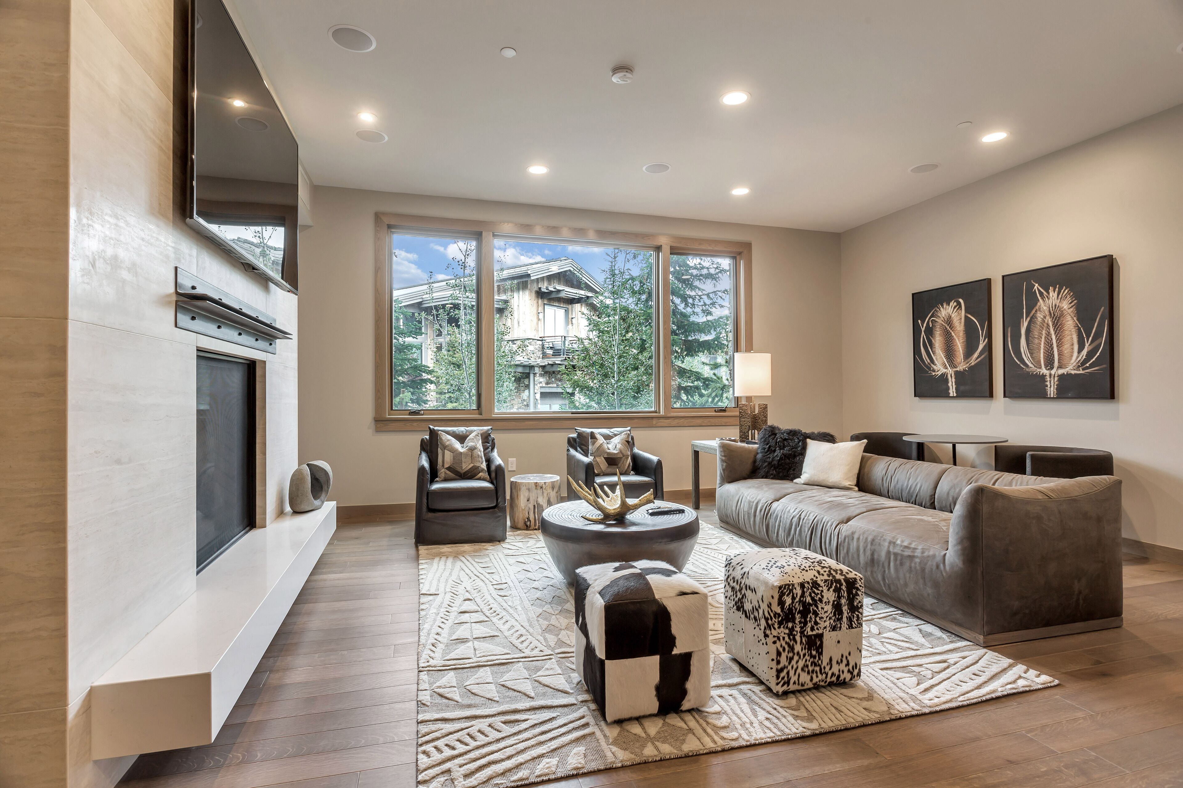 A modern living room with a fireplace, large windows, and a cozy seating area.