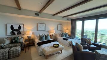 A spacious living room with a large window, a sofa set, a coffee table, and a fireplace.