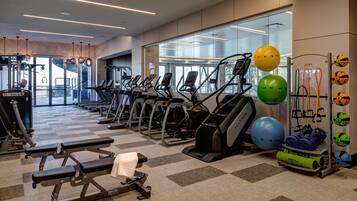 A modern gym with treadmills, elliptical machines, and various exercise balls.