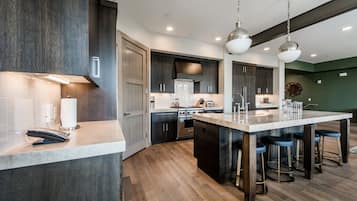 A modern kitchen with dark wood cabinets, a central island with bar stools, and stainless steel appliances.