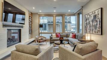 A spacious living room with a large window, a fireplace, and a modern sofa set.