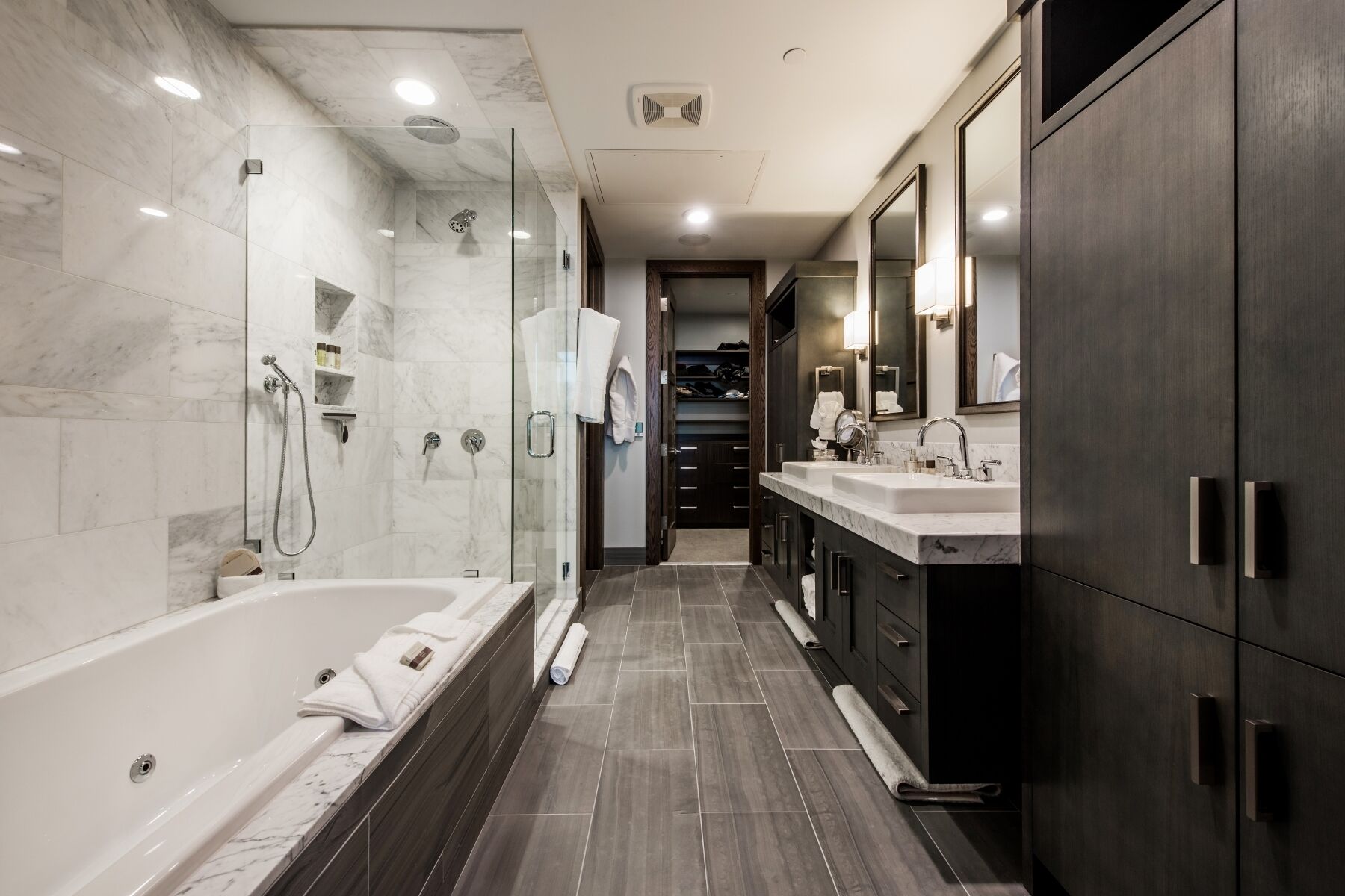 A modern bathroom with a glass-enclosed shower, a bathtub, and a vanity with a large mirror.