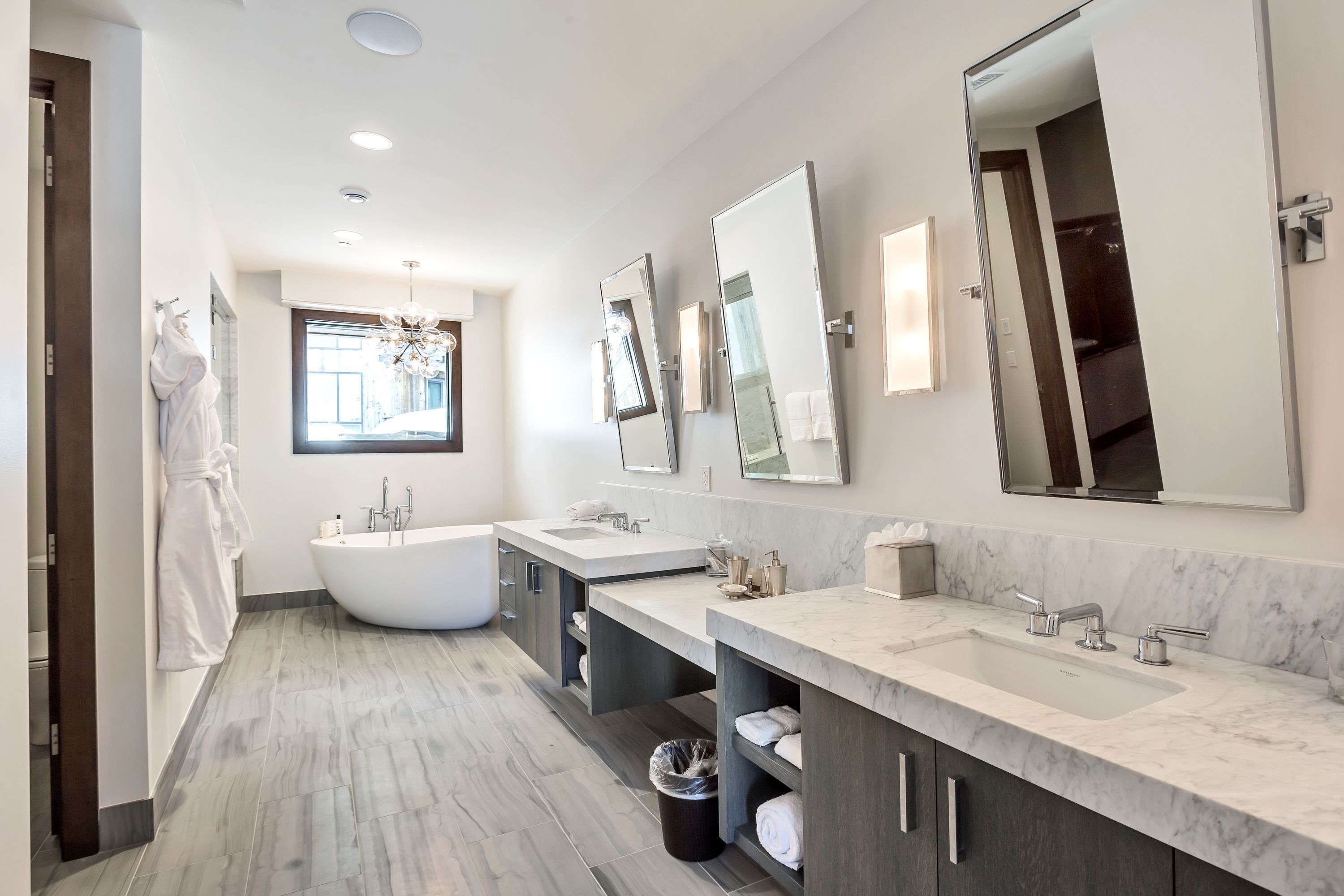 A modern bathroom with a freestanding bathtub, two sinks, and ample storage space.
