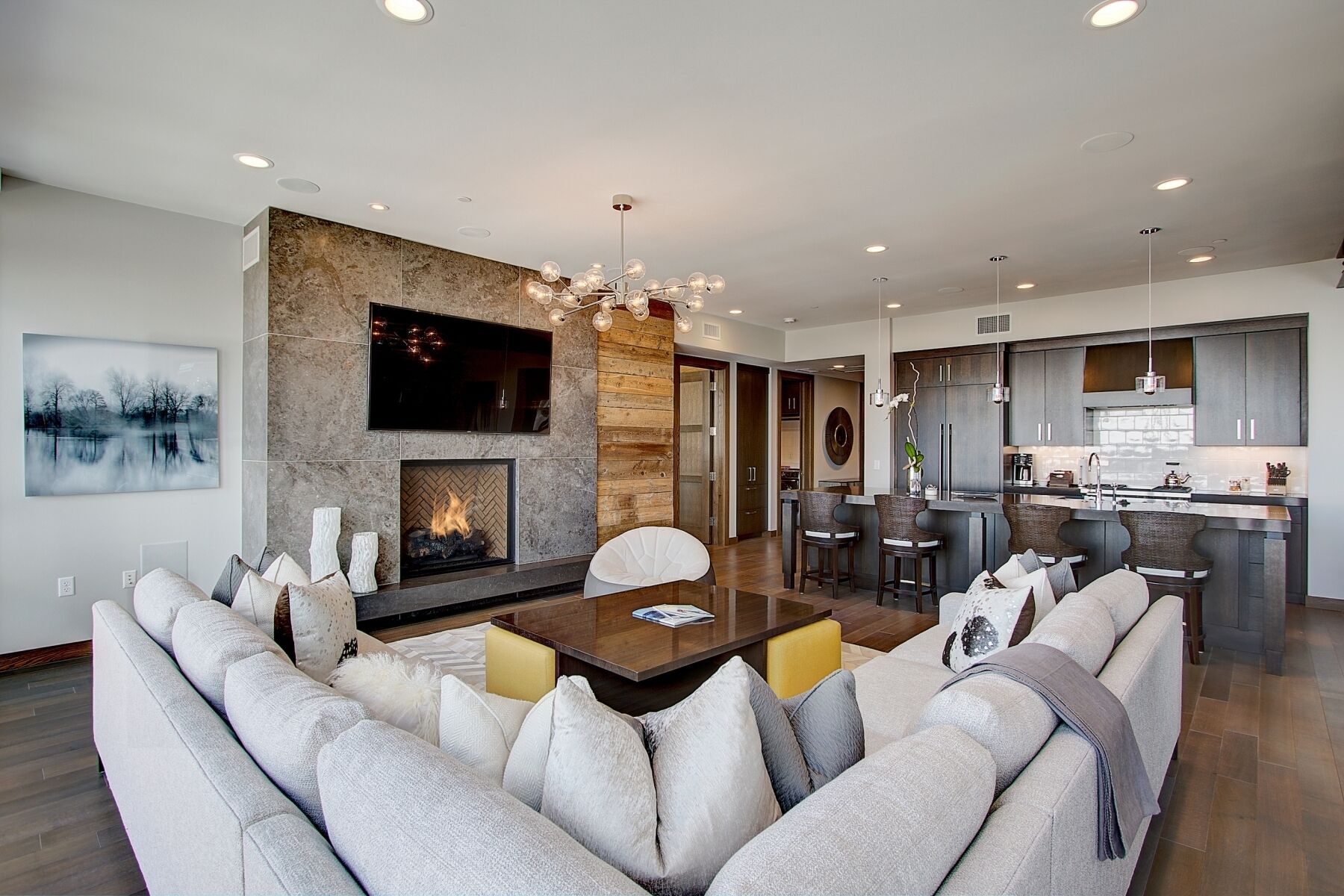 A modern living room with a fireplace, a dining area, and a kitchen.