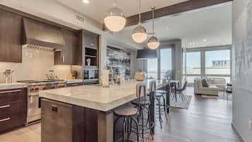 A modern kitchen with a large island, bar stools, and a dining area with a sofa and table.