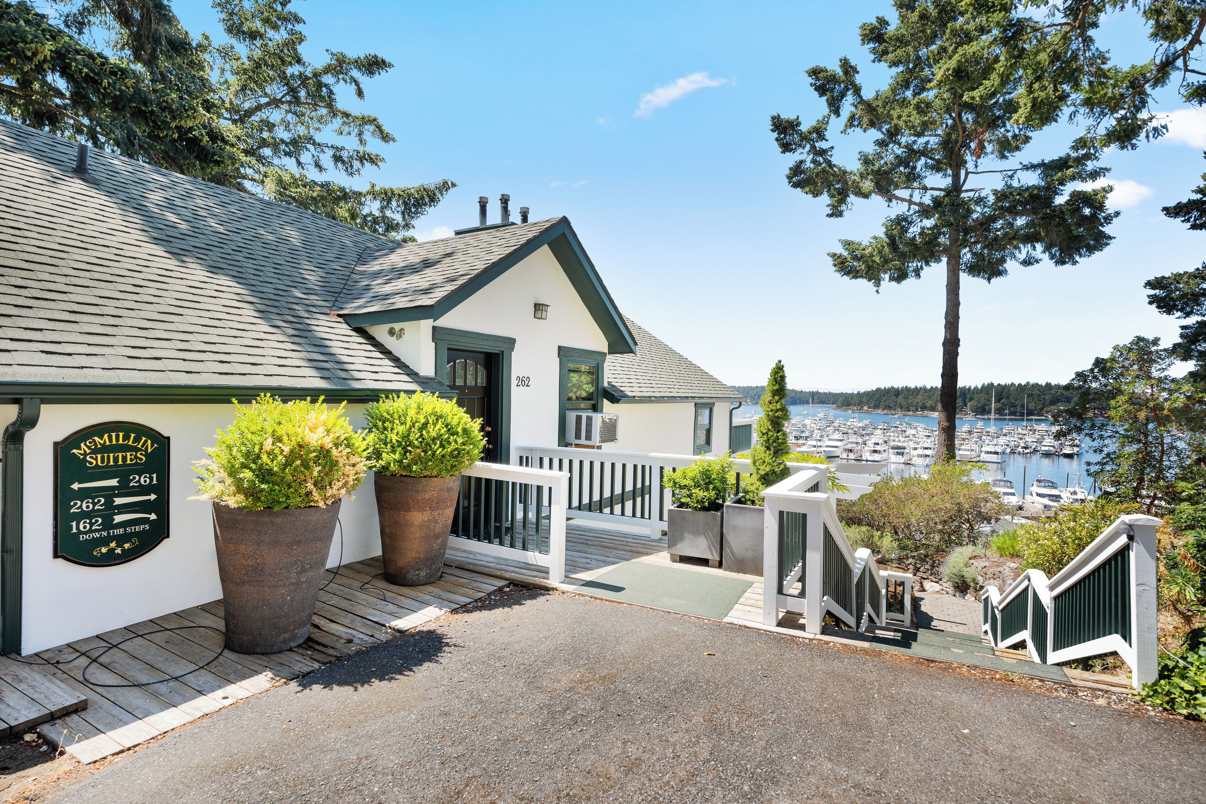 A coastal building with a sign indicating McMillin Suites, featuring a view of the marina and boats.