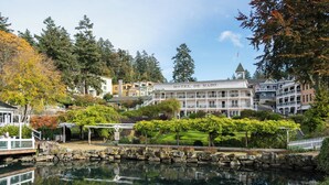 A hotel with a large building, a pond in front, and trees around. - Roche Harbor Resort (Friday Harbor)