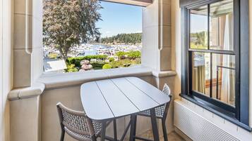 Varanda com mesa e cadeiras, vista para um porto e janela com cortinas.