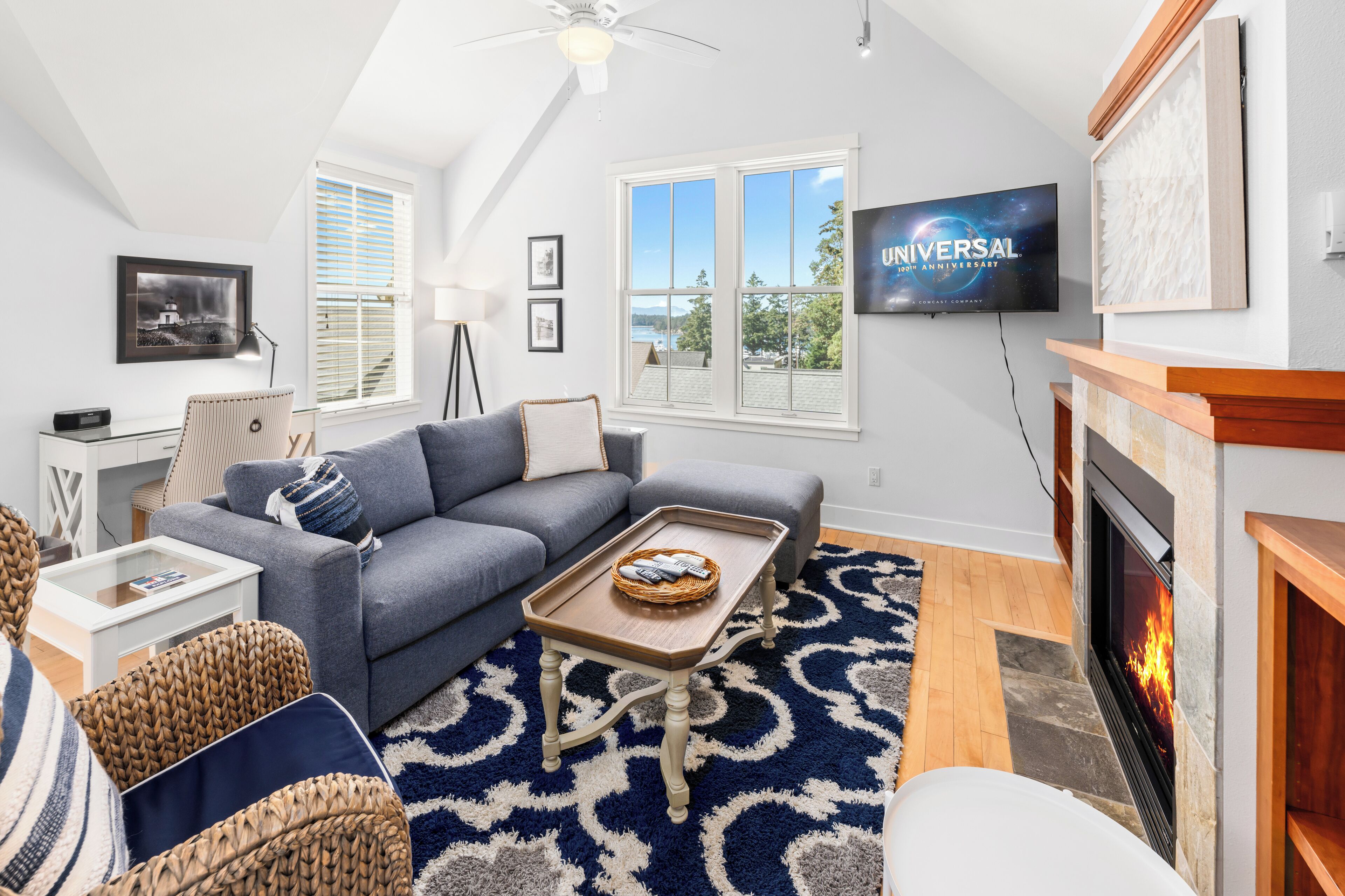 A modern living room with a gray sofa, a coffee table, a fireplace, and a television mounted on the wall.