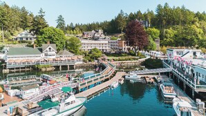 A waterfront hotel with multiple docked boats, a pier, and a view of the surrounding forested area. - Roche Harbor Resort (Friday Harbor)